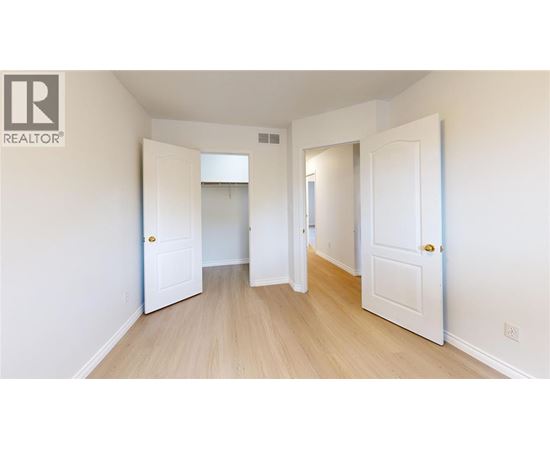 A white door is open to a hallway with wood floors.