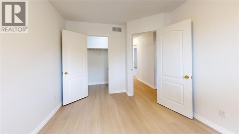 A white door is open to a hallway with wood floors.