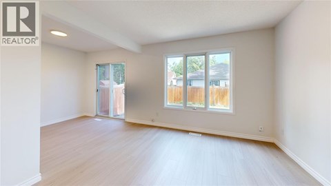 A spacious room with a sliding glass door leading to a backyard.