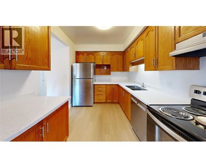 A kitchen with wooden cabinets and a stainless steel refrigerator.