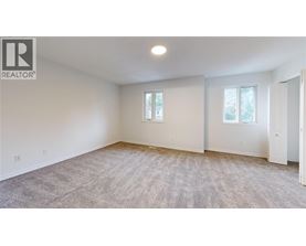 A spacious room with a carpeted floor and two windows.