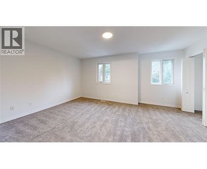 A spacious room with a carpeted floor and two windows.