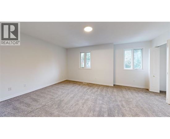 A spacious room with a carpeted floor and two windows.