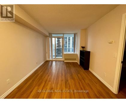 A room with wooden floors and a window with a view of a building outside.