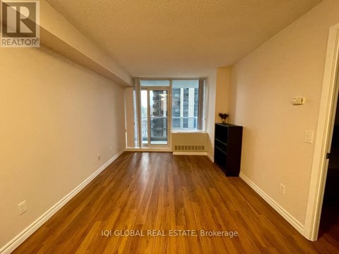 A room with wooden floors and a window with a view of a building outside.