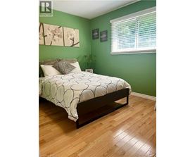 A bedroom with a bed, a window with blinds, and a plant.