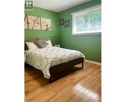 A bedroom with a bed, a window with blinds, and a plant.