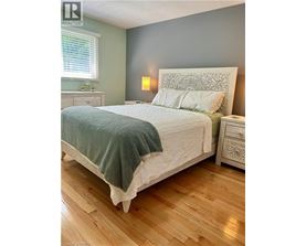 A bedroom with a large bed and wooden floors.