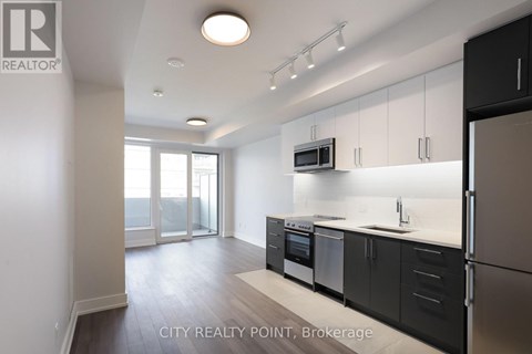 A modern kitchen with black cabinets and stainless steel appliances.