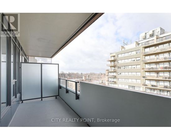 A balcony with a glass railing and a view of a cityscape.