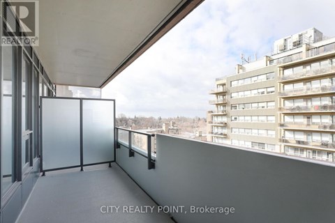 A balcony with a glass railing and a view of a cityscape.