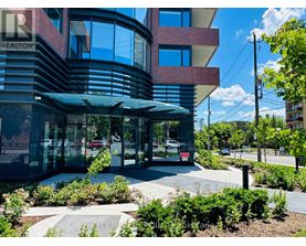 A modern building with a glass entrance and a landscaped area in front.