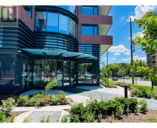 A modern building with a glass entrance and a landscaped area in front.