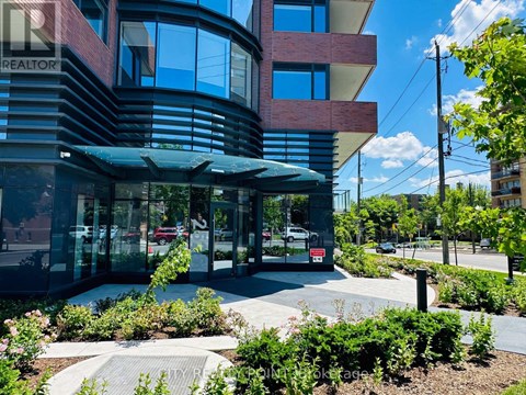 A modern building with a glass entrance and a landscaped area in front.