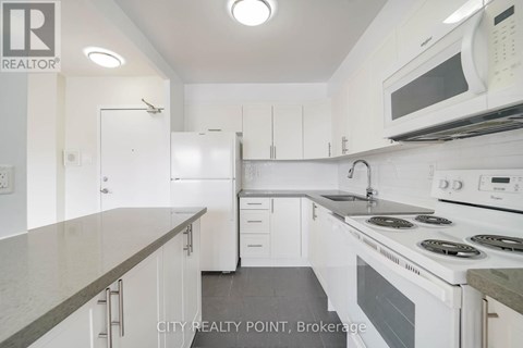 A white kitchen with a microwave on the wall.