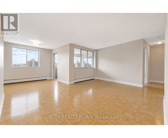 A spacious room with wooden flooring and large windows at City Realty Point, Brokerage.