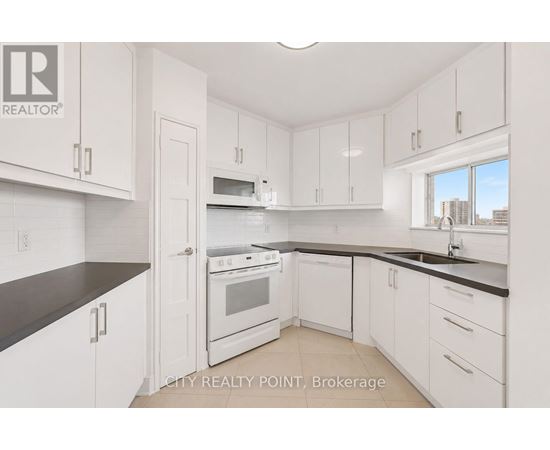 A kitchen with white cabinets and black countertops.
