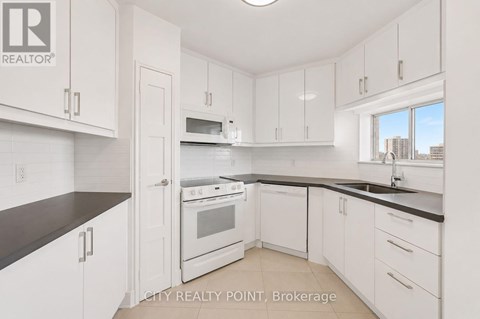 A kitchen with white cabinets and black countertops.