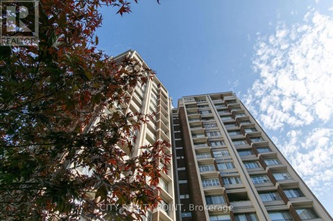 Two buildings are seen from the ground with trees in the foreground.