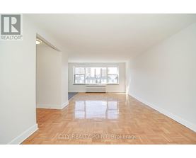 A spacious room with wooden flooring and a window letting in natural light.