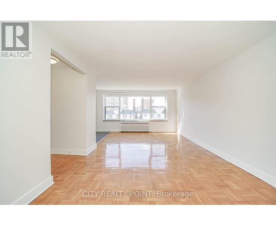 A spacious room with wooden flooring and a window letting in natural light.