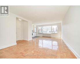A spacious room with wooden flooring and a large window.