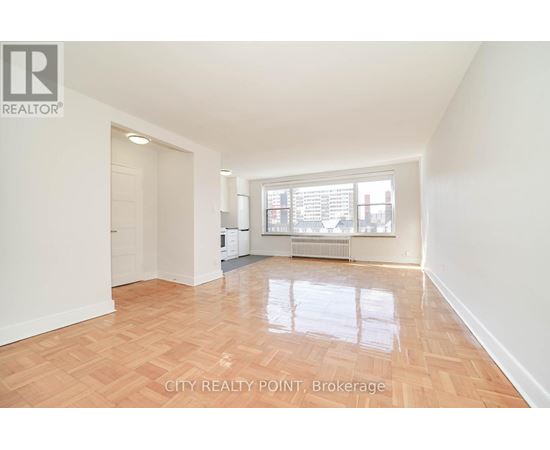 A spacious room with wooden flooring and a large window.