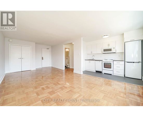 A kitchen with white appliances and wooden floors.