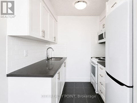 A kitchen with white cabinets and a black counter top.