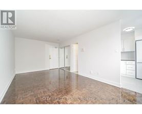 A spacious room with wooden flooring and white walls.