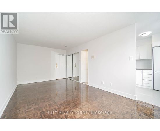 A spacious room with wooden flooring and white walls.