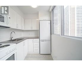 A white refrigerator is in a kitchen with white cabinets.