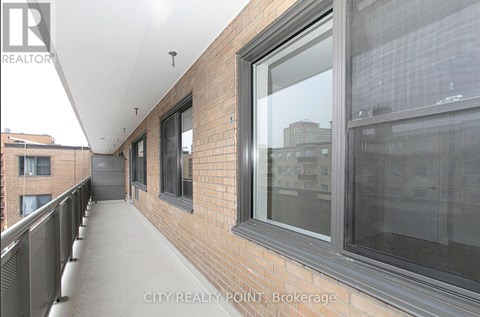 A balcony with a metal railing and a brick wall.