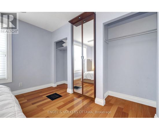 A bedroom with a bed on the left and a mirror on the right.