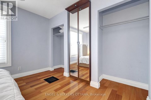 A bedroom with a bed on the left and a mirror on the right.