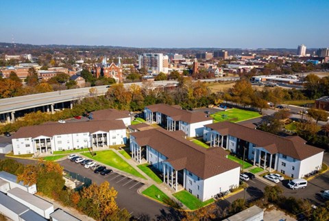 A large white building with a brown roof is surrounded by a parking lot.