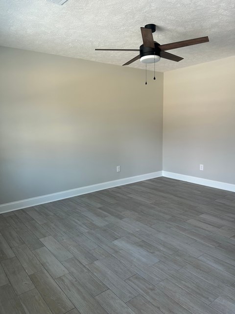 A room with a ceiling fan and wooden flooring.