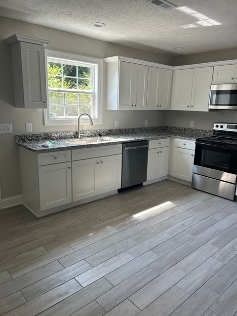 A kitchen with white cabinets and a black stove top oven.