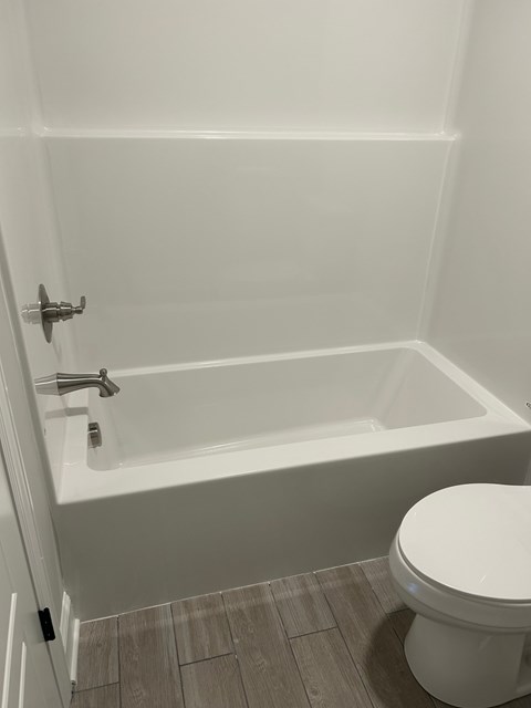 A white toilet sits next to a bathtub in a bathroom.