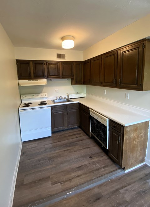 A kitchen with wooden cabinets and a white stove top oven.