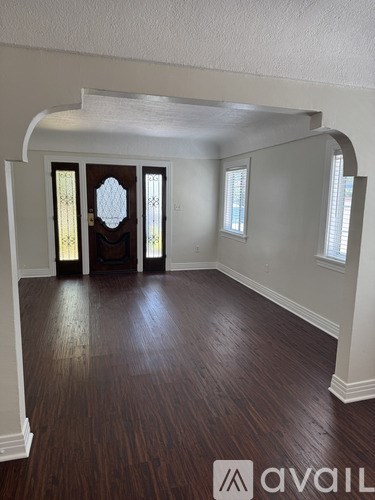 A room with wood flooring and arched doorways.