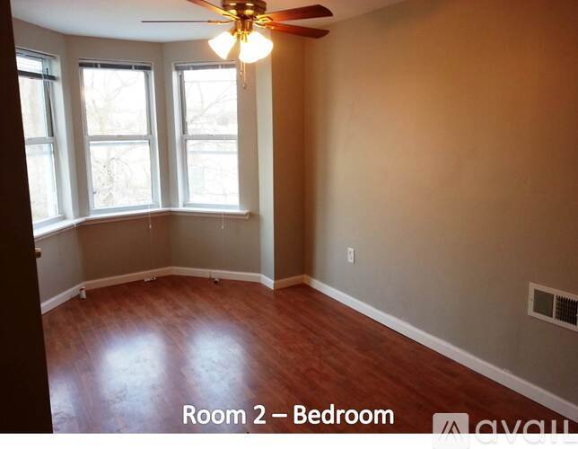 A bedroom with a ceiling fan and hardwood floors.