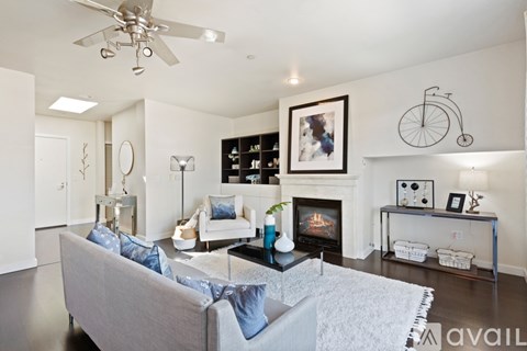 A living room with a grey couch and a fireplace.