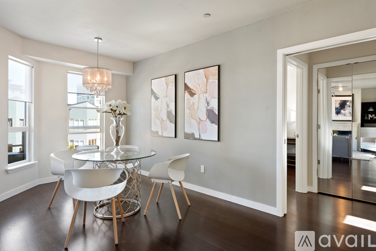 A modern dining room with a glass table and white chairs.