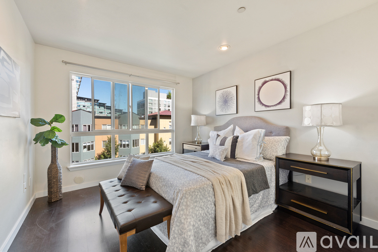 A bedroom with a large bed and a bench in front of a window.