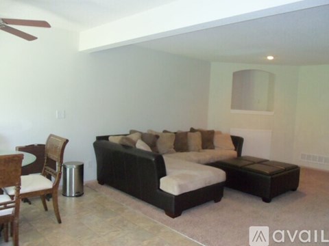 A living room with a black couch and a wooden chair.