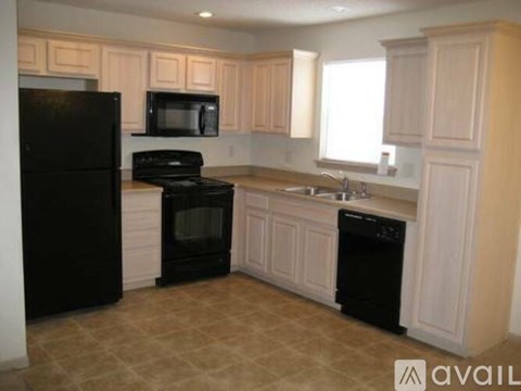 A kitchen with black appliances and wooden cabinets.