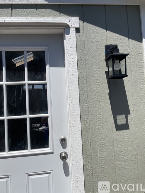 A white door with a window and a black lantern on the wall.