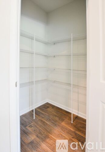 A walk in closet with shelves and a wooden floor.