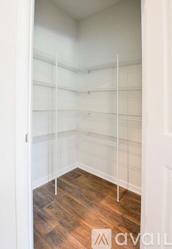 A walk in closet with shelves and a wooden floor.